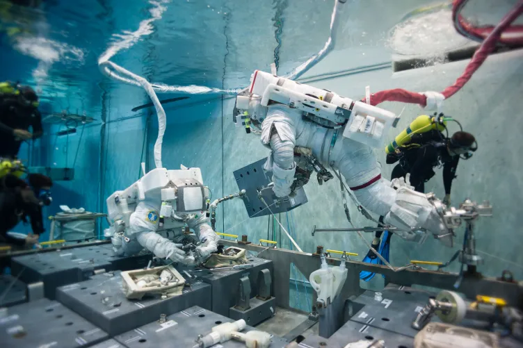 Two astronauts and one diver underwater at NASA's Neutral Buoyancy Lab