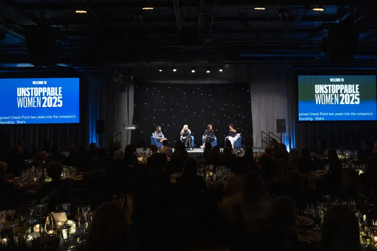 Several women speaking on stage in front of a crown for Unstoppable Women 2025.