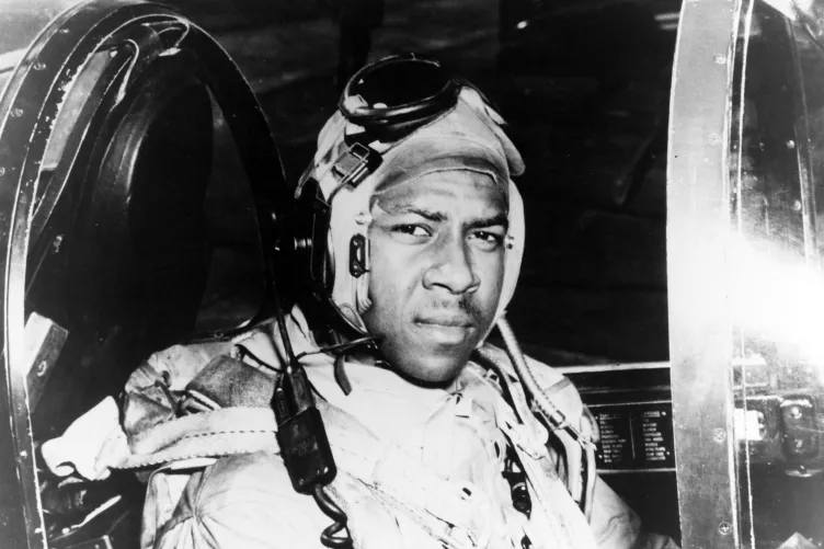 Jesse Brown in his flight suit and aviator helmet in the cockpit of an F4U Corsair.