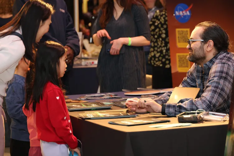 Kids standing at an information table learning about space during Kids Week