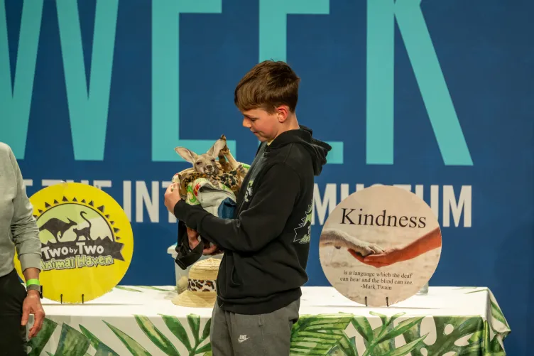 A kid holding a wallaby on stage during a presentation
