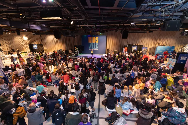 A large crowd of kids and parents gather around for a stage during Kids Week