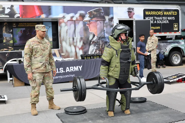 Visitors trying on U.S. Army gear and lifting weights during Fleet Week.