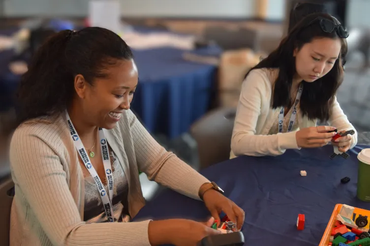 Two women engaged in construction with snap-together building blocks