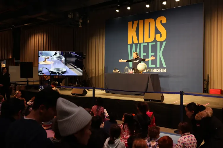 A presenter leading a science demonstration for children during Kids Week.