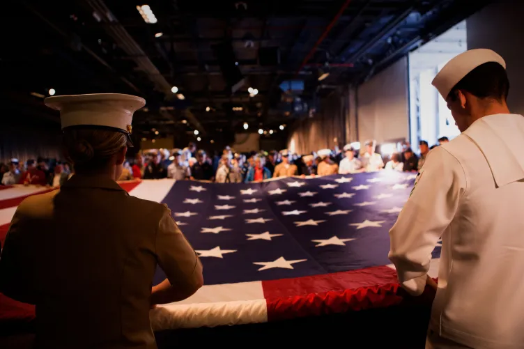 Military crew members unveiling a flag during a ceremony