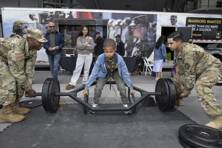 U.S. military personnel engaging with visitors in an interactive activity at the Intrepid Museum on Pier 86 during a public event.