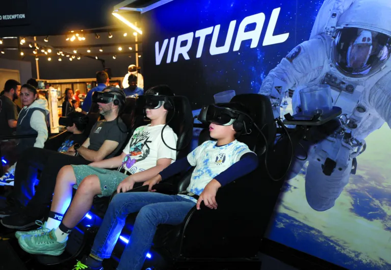 Visitors seated and wearing goggles for the Virtual Reality experience in the Space Shuttle Pavilion.