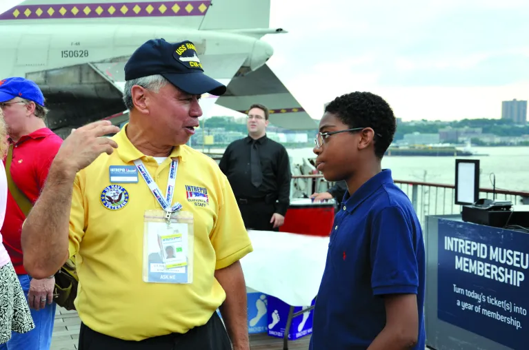 A veteran speaks with a child on the flight deck.