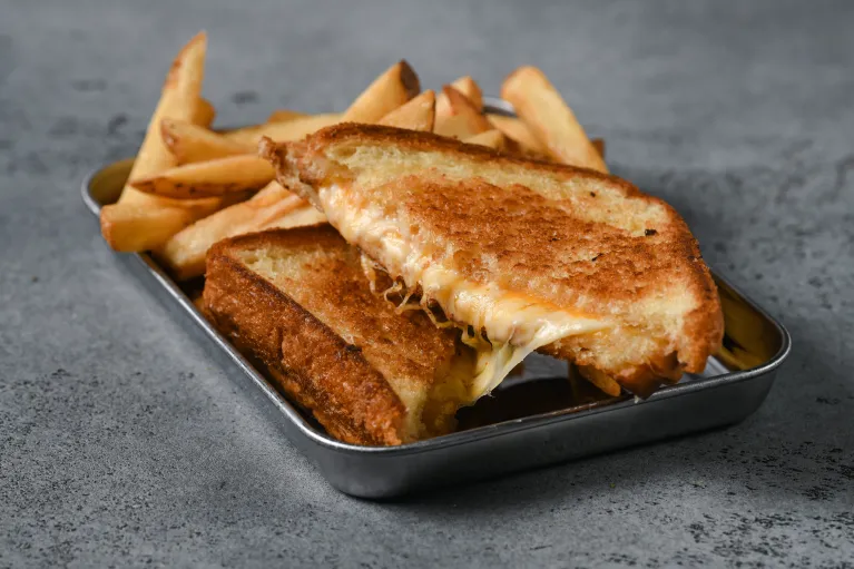 A grilled cheese sandwich and fries on a tray