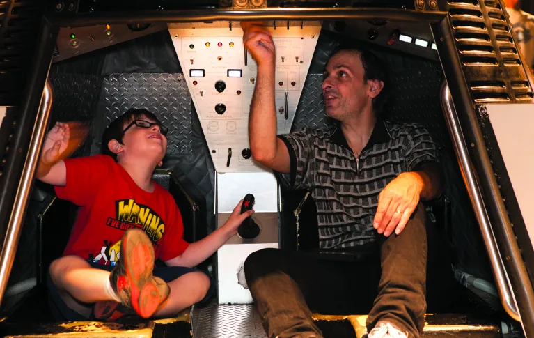 A parent and child playing in a mock capsule in the Exploreum.