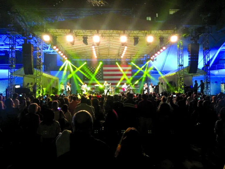 A band is performing at night on a stage in front of a large crowd