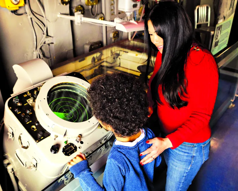 A parent and child playing with a radar scanner in the Exploreum