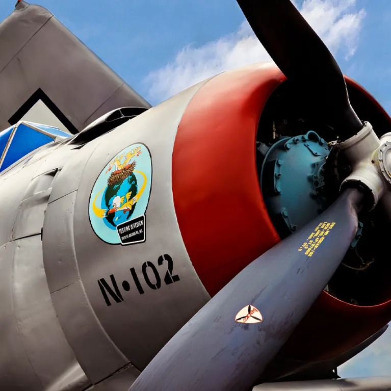 A close up of the propeller of an airplane with a blue sky in the background.
