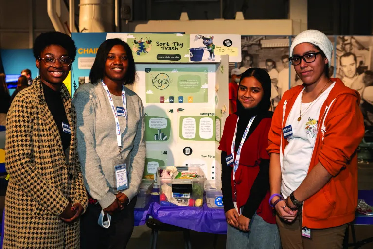 Girls in front of a trifold presentation with a model on a table