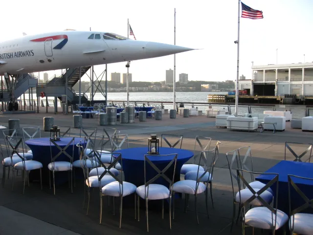 Round tables and chairs set up beneath the Concorde