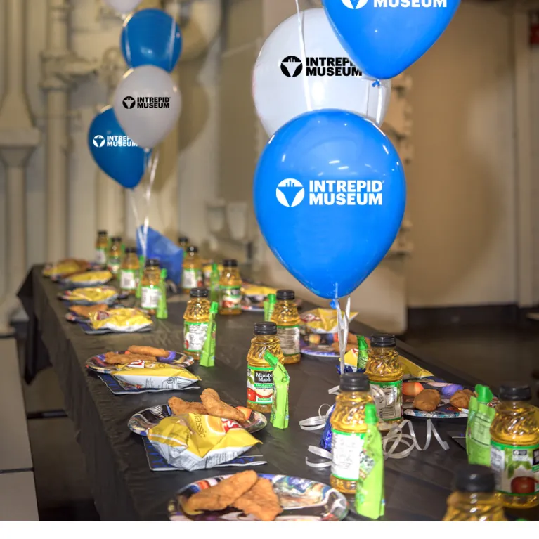 A table is set with snacks and blue and white balloons.