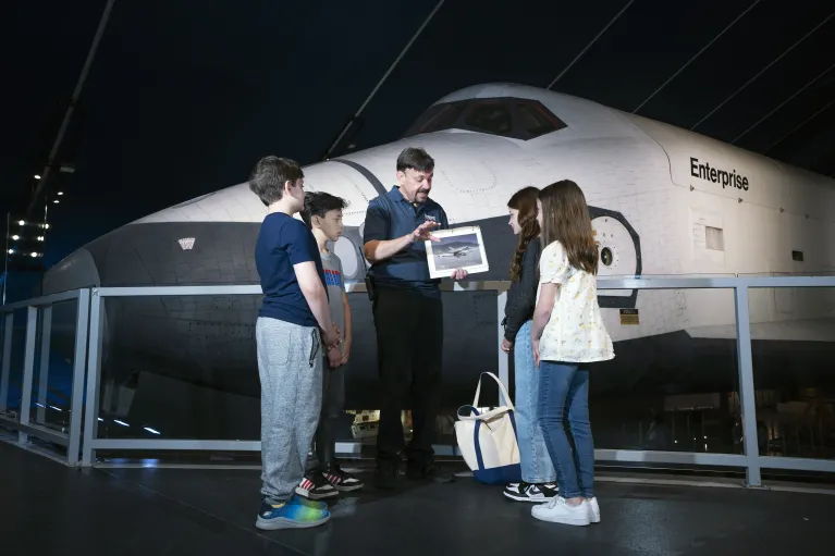 Intrepid Museum Educator with a group of kids in front of the Space Shuttle Enterprise.