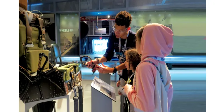 A Museum educator shows two girls how aircraft ejection seat works