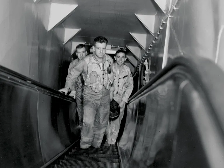 Three pilots standing in the middle of the Intrepid&#039;s pilot escalator.