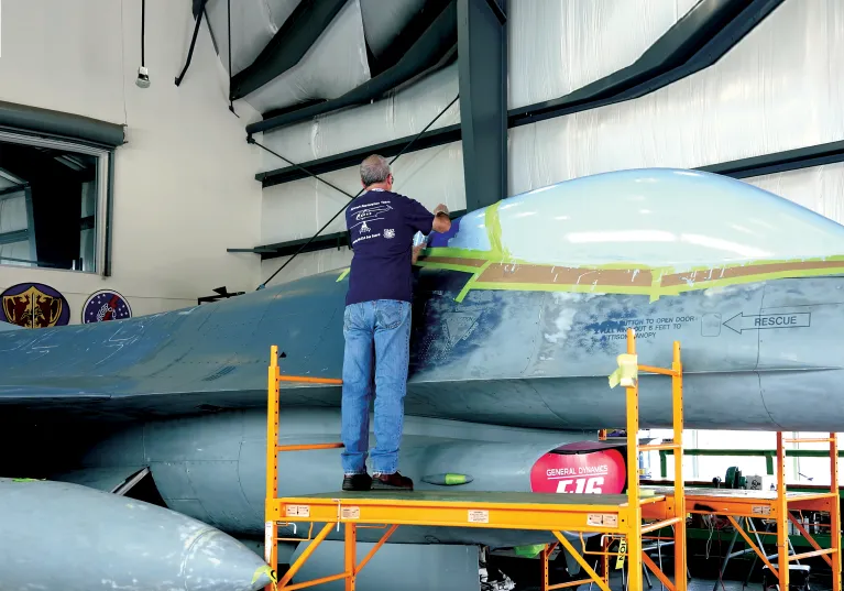 Aircraft restoration specialist working on an F-16 aircraft located at the Restoration Hangar at the Intrepid Flight Deck.