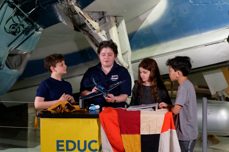 A museum educator with three children learning about aircrafts at an education station