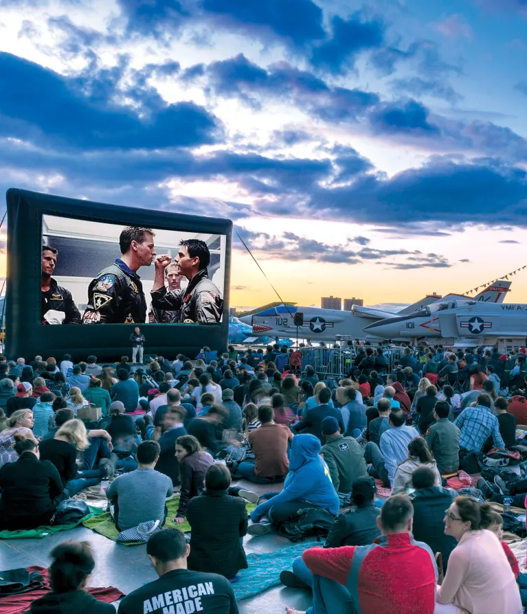 Movie Night Crowd at the Flight Deck during sunset, large movie screen, and Aircraft in the background.