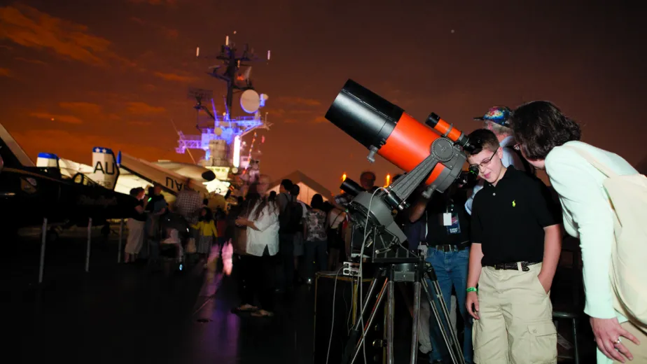 People using telescopes on the flight deck to look at the night sky.