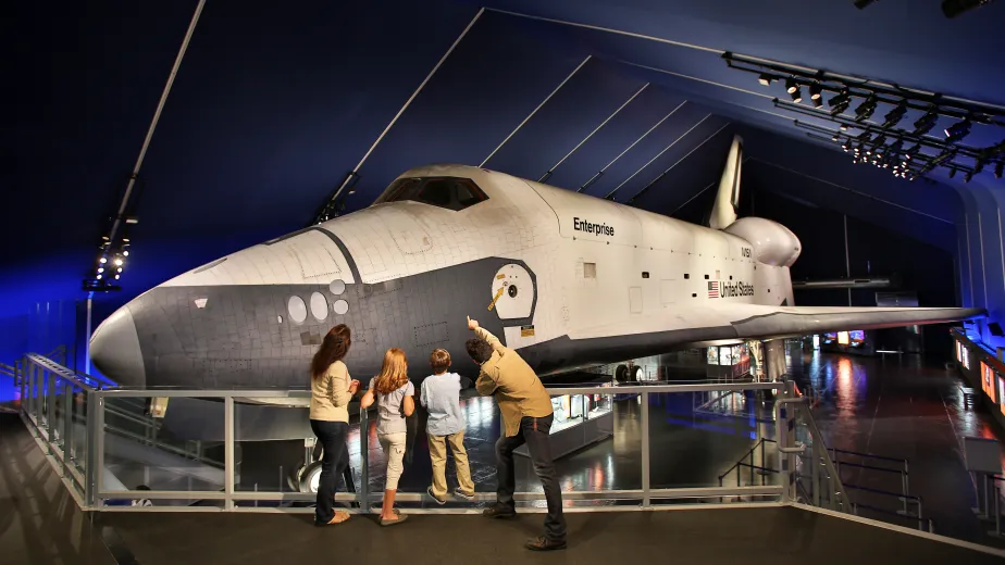 A family looks at the space shuttle Enterprise from an elevated viewing platform inside the Space Shuttle Pavilion