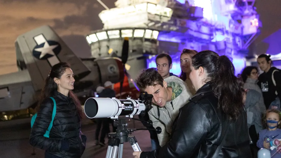 Visitors are looking through a telescope on the flight deck.