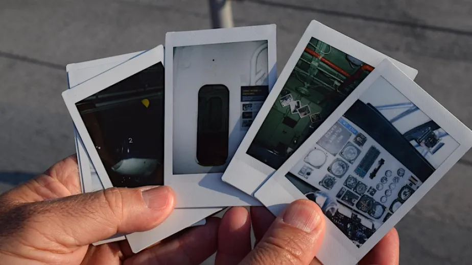 holding polaroid pictures of onboard the intrepid museum