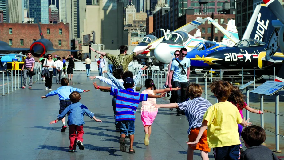Children on the flight deck with their arms out like they are flying.