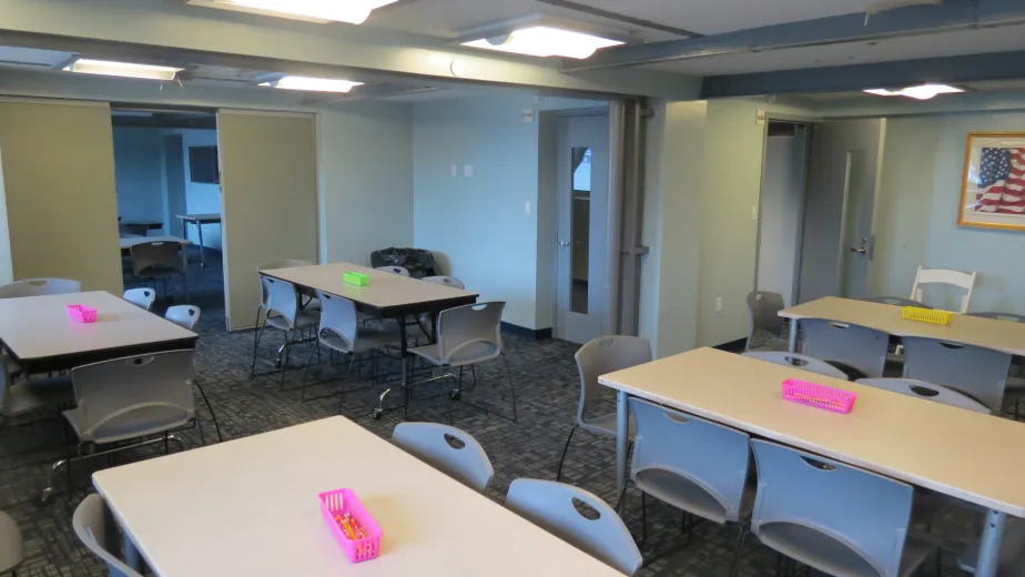 A classroom with rectangle tables and chairs around them