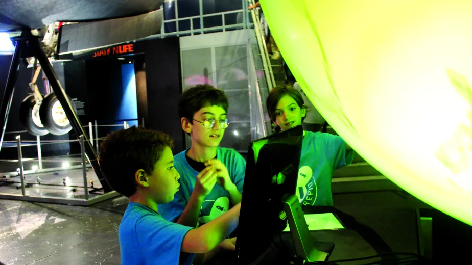 Students looking at a monitor in the Space Shuttle Pavilion
