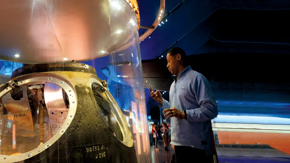 Man looking inside the Soyuz capsule exhibit