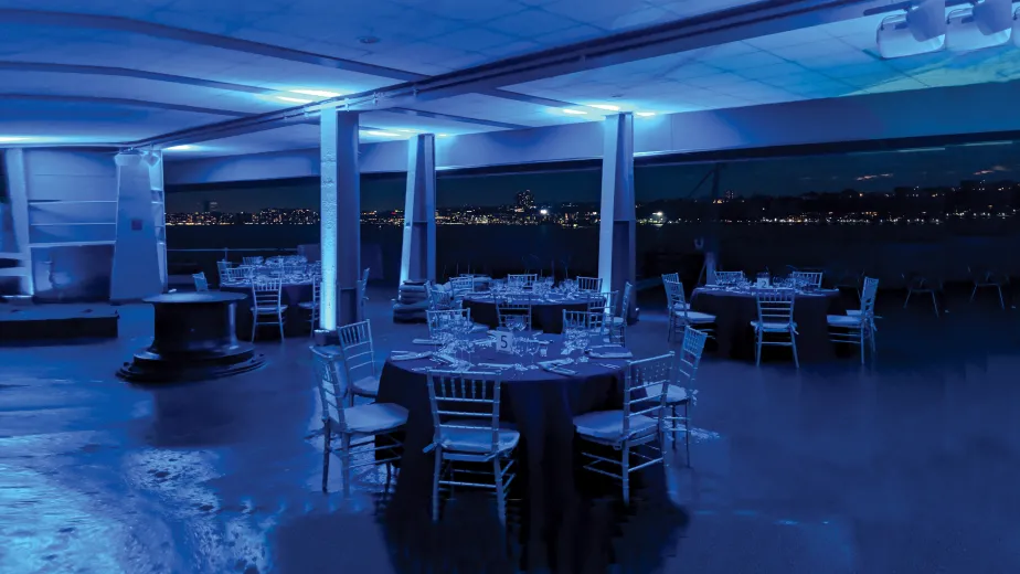 Photo of the Fantail setup for a seat down dinner with a view of the Hudson River and New Jersey skyline.