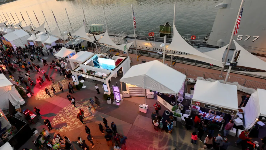 Pier 86 at night, illuminated by vibrant lights with event tents set up, with crowds creating a lively atmosphere.