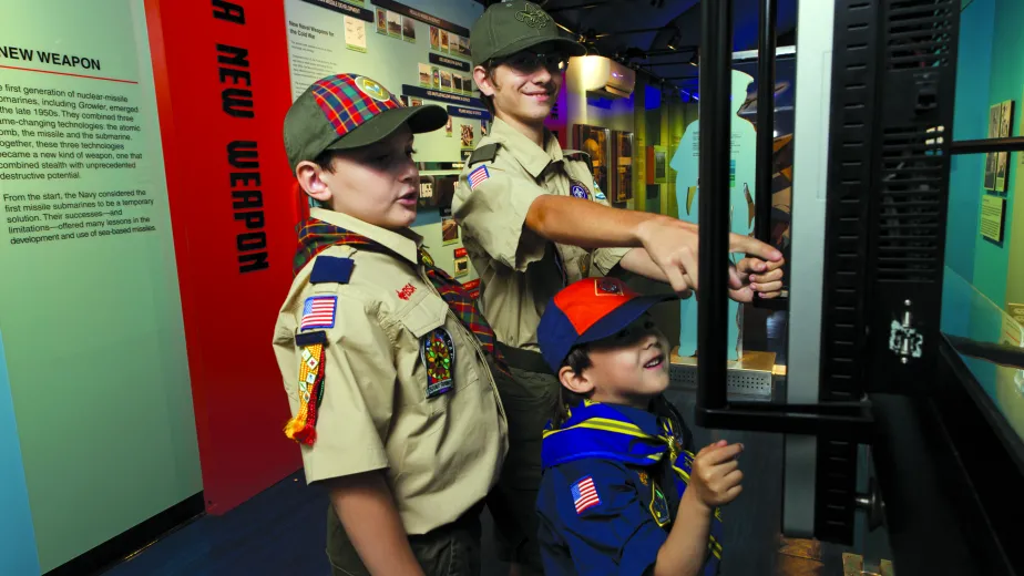 Three Boy Scouts engaging with an exhibit.