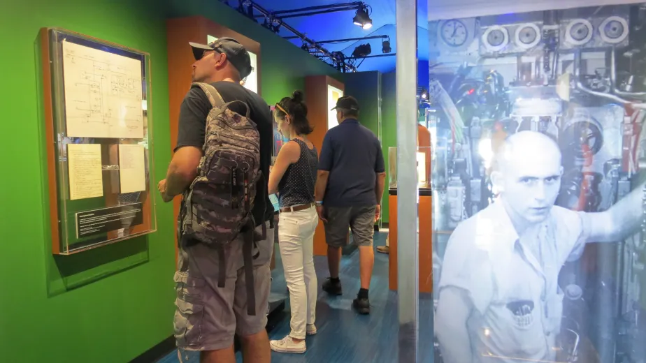 Intrepid after hours hero image - A patron at the intrepid museum reading intently about one of the exhibits