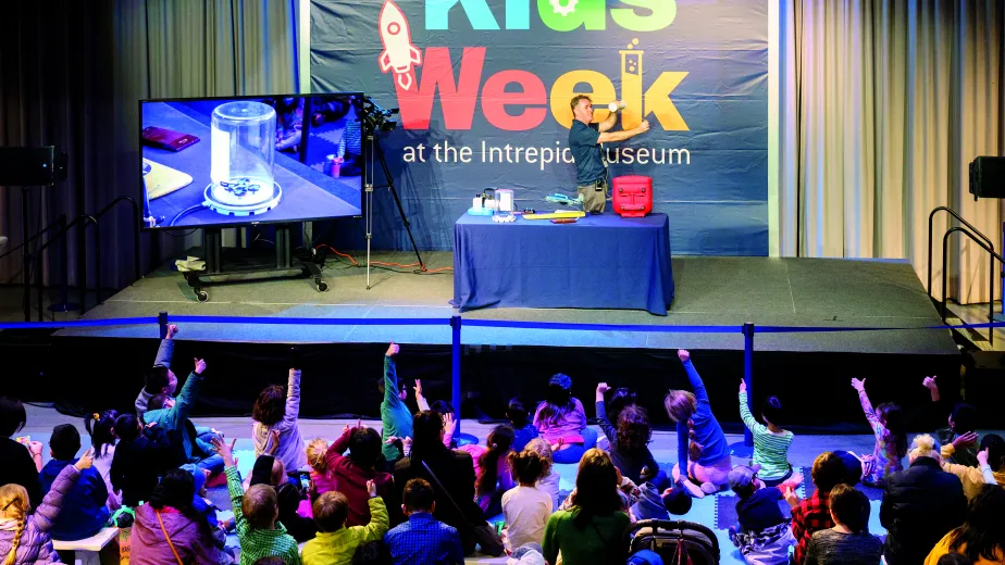 An Intrepid Museum educator presenting to kids in the Exploreum interactive hall during Kids Week