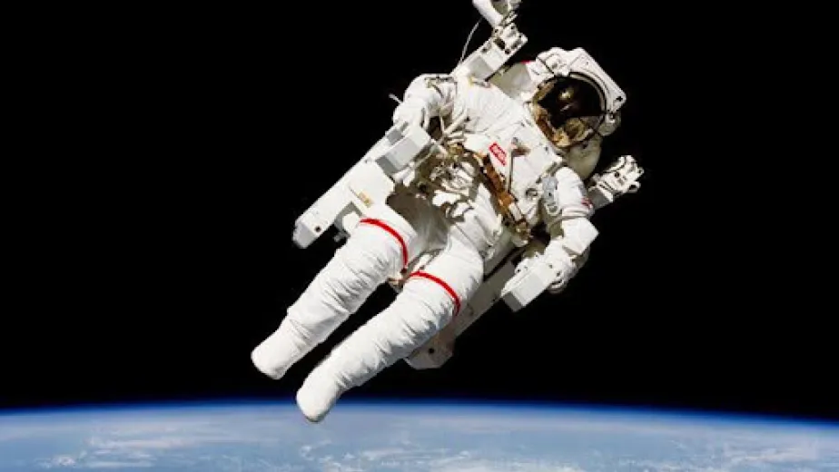 An astronaut floats in space, Earth seen below them.