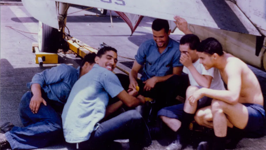 A group of Spanish sailors sitting on the flight deck of the Intrepid.