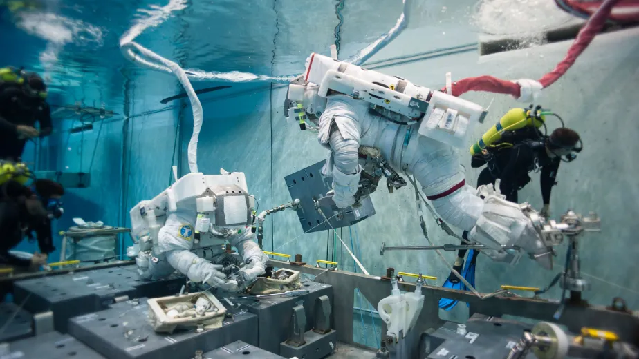 Two astronauts and one diver underwater at NASA's Neutral Buoyancy Lab