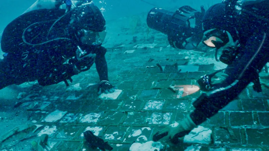2 divers examining tiles on the ocean floor