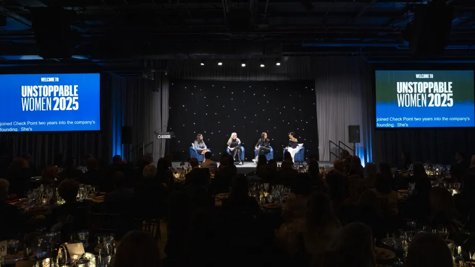 Several women speaking on stage in front of a crown for Unstoppable Women 2025.