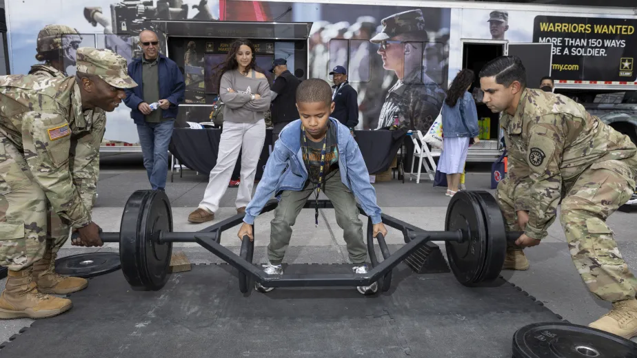 Visitors trying on U.S. Army gear and lifting weights during Fleet Week.