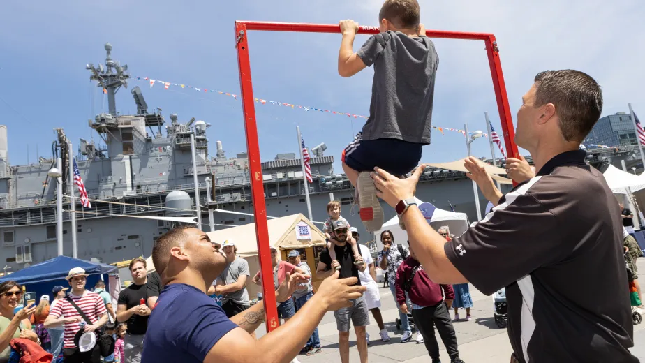 U.S. military personnel engaging with visitors in an interactive activity at the Intrepid Museum on Pier 86 during a public event.