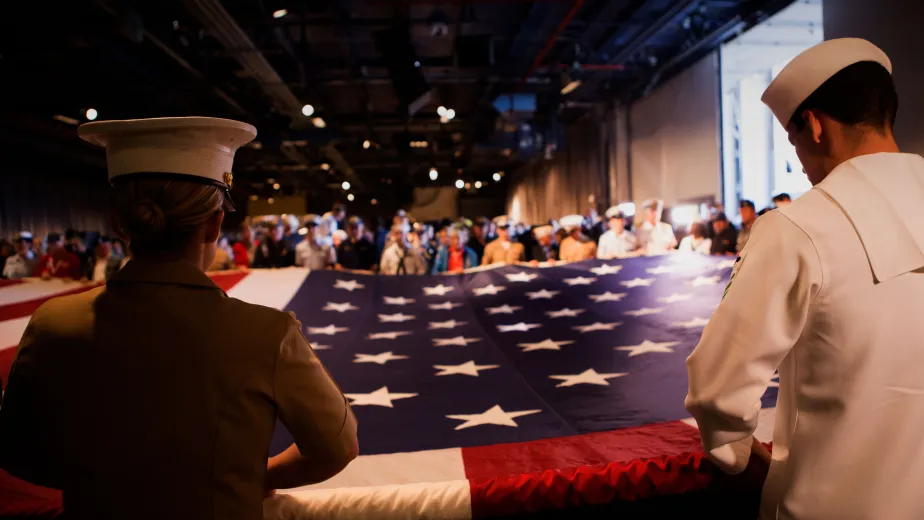 Military crew members unveiling a flag during a ceremony