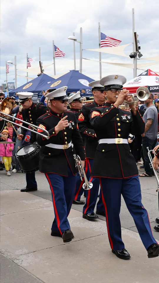 U.S. military personnel marching at the Intrepid Museum on Pier 86 during a ceremonial event.