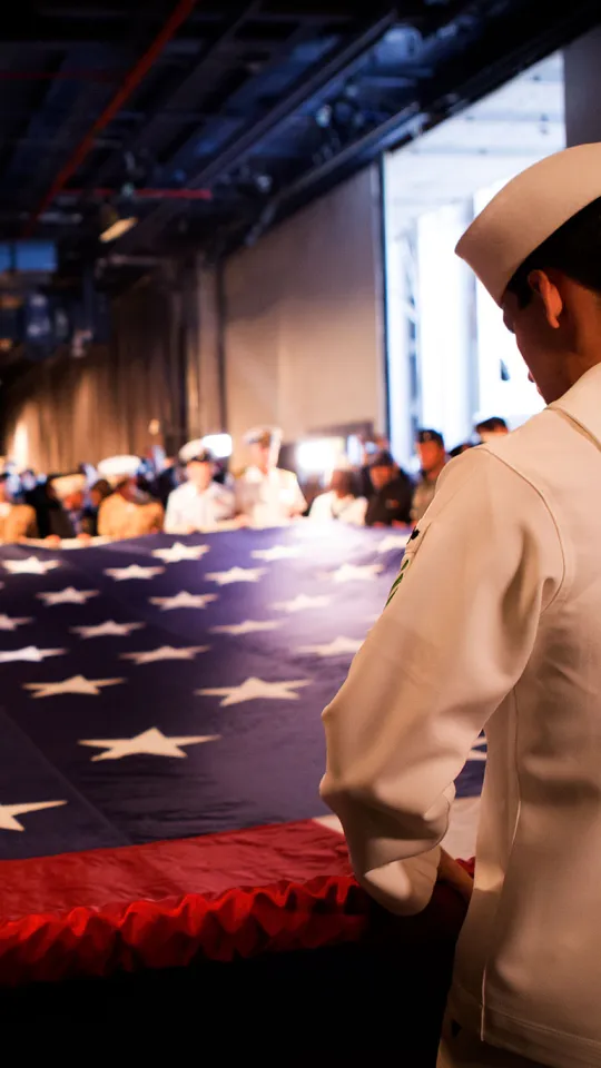 Military crew members unveiling a flag during a ceremony